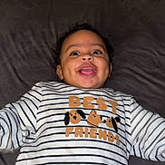 Djelann a rejoint le concours — aidez-le/la à gagner de superbes lots ! baby, child, smiling, striped_shirt, best_friends, dog_illustration, lying_down, dimples, happy, cute, face, portrait, indoors, clothing, sleeves, person, infant, young_child, bed, pillow