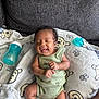 Coa is registered to the contest to win money with this photo: baby, smiling, infant, onesie, blanket, bear_pattern, couch, pacifier, bottle, happy, face, skin, hair, hand, foot, child, indoors, comfort, resting, cute