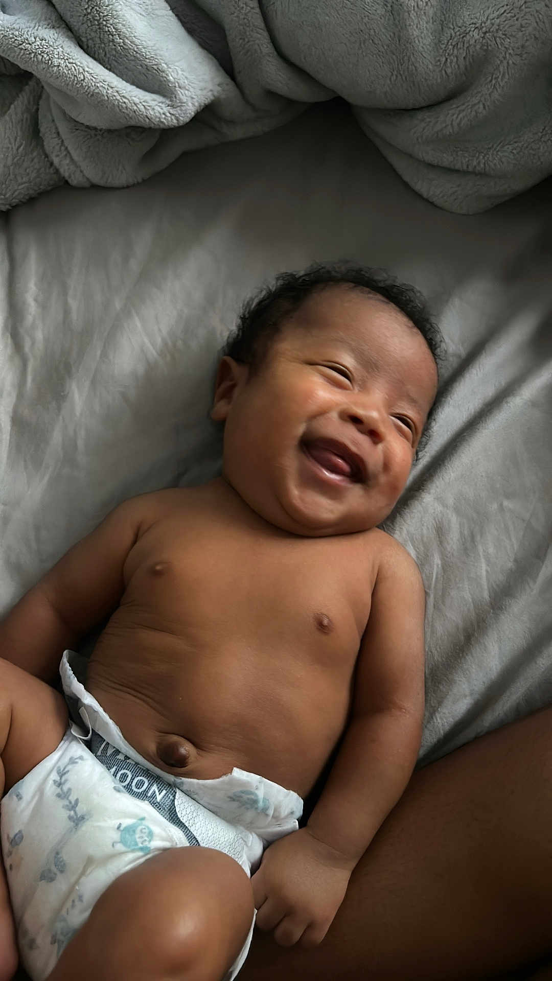 Coa is registered to the contest to win money with this photo: baby, smiling, diaper, infant, lying_down, happy, skin, fleece_blanket, blanket, comfort, cute, child, person, relaxation, home, portrait, young, sleepwear, chubby, indoors