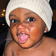 Onyx joined the competition — help win amazing prizes! baby, child, face, smile, tongue, hat, knit_hat, cozy, happy, portrait, skin, eyes, mouth, cheeks, cute, infant, closeup, expression, warm_lighting, dark_background