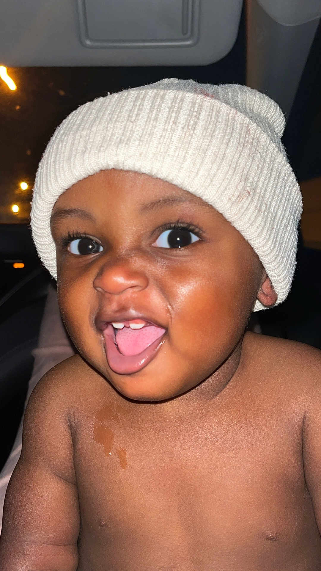 Onyx joined the competition — help win amazing prizes! baby, child, face, smile, tongue, hat, knit_hat, cozy, happy, portrait, skin, eyes, mouth, cheeks, cute, infant, closeup, expression, warm_lighting, dark_background