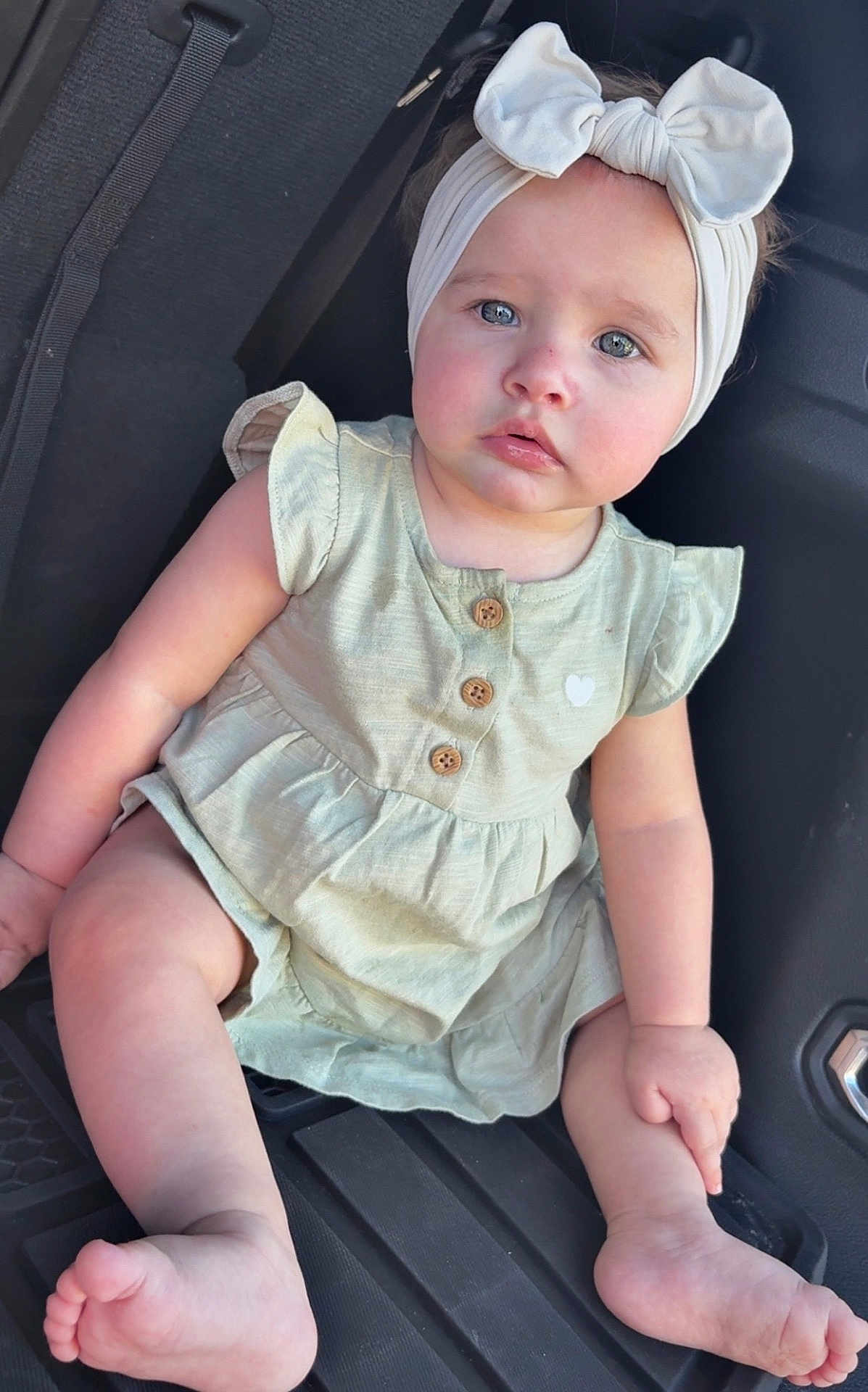 Arely is registered to the contest to win money with this photo: baby, child, infant, girl, headband, bow, blue_eyes, dress, sitting, car_seat, wooden_buttons, cute, innocent, soft_skin, natural_light, closeup, portrait, legs, feet, hand