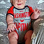 baby, infant, smiling, onesie, clothing, sitting, cushion, cloud_pattern, hand, face, cheeks, legs, feet, arm, blue_eyes, red_hair, indoor, portrait, happy, child