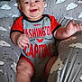 baby, child, smiling, onesie, clothing, cushion, cloud_pattern, indoor, happy, person, infant, cute, sitting, plush, red, gray, short_sleeves, soft, face, cheerful
