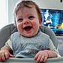 William is registered to the contest to win money with this photo: baby, smiling, high_chair, bib, happy, child, indoor, toddler, face, hands, clothing, furniture, television, living_room, hair, cute, expression, person, seat, home