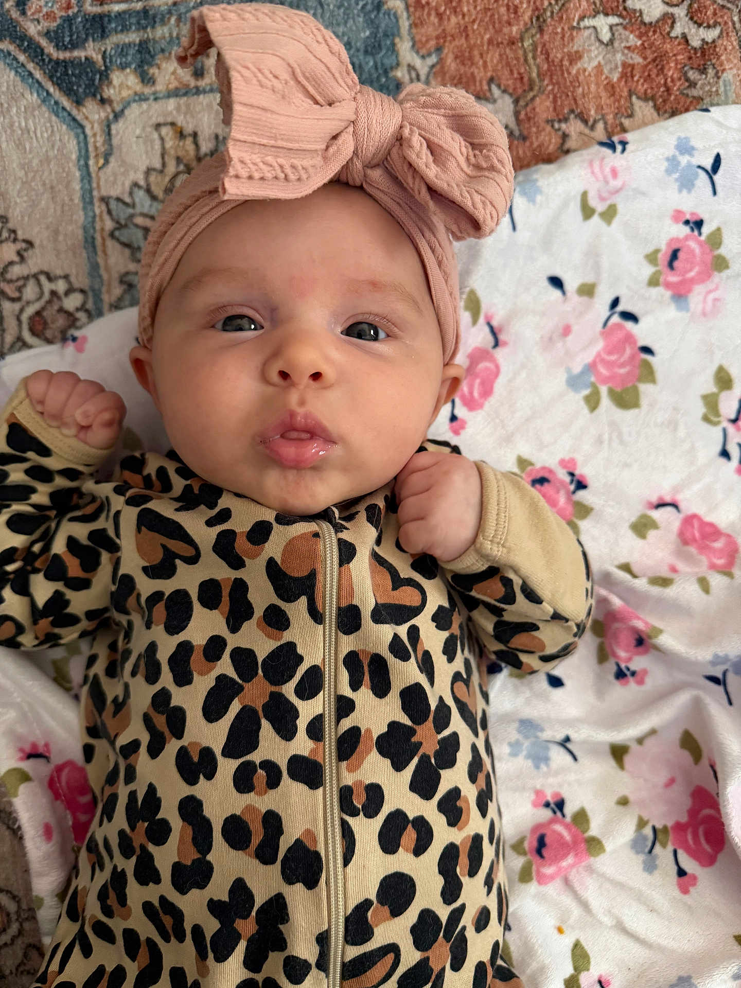 Emersyn is registered to the contest to win money with this photo: baby, infant, headband, bow, leopard_print, onesie, pout, face, skin, blanket, floral_pattern, cute, expression, lying_down, child, small_hands, indoors, soft_texture, cozy, adorable