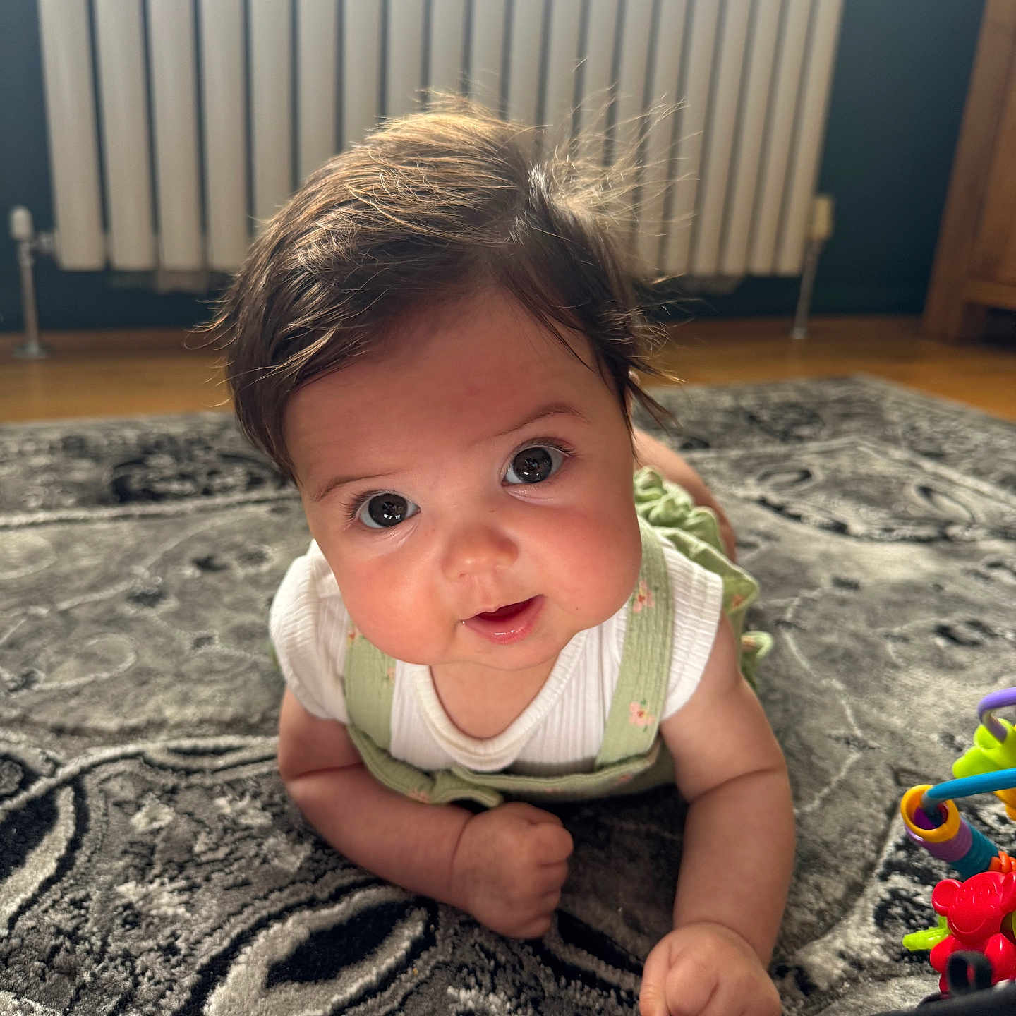 Havana joined the competition — help win amazing prizes! baby, child, closeup, clothing, crawling, curious, cute, eyes, face, floor, green_overalls, hair, home, indoor, infant, portrait, rug, smiling, toy, white_shirt