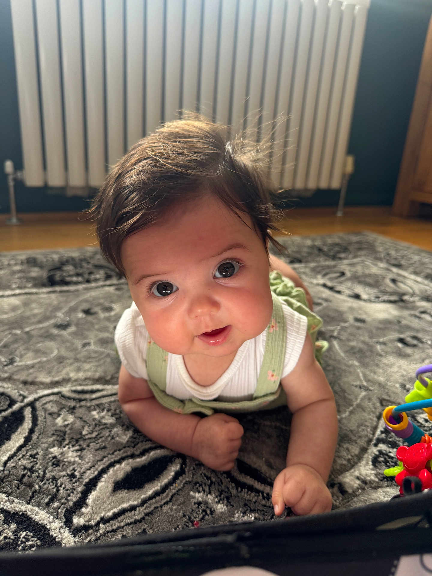 Havana joined the competition — help win amazing prizes! baby, infant, child, cute, face, eyes, hair, rug, floor, toy, home, indoor, crawling, clothing, white_shirt, green_overalls, curious, smiling, closeup, portrait