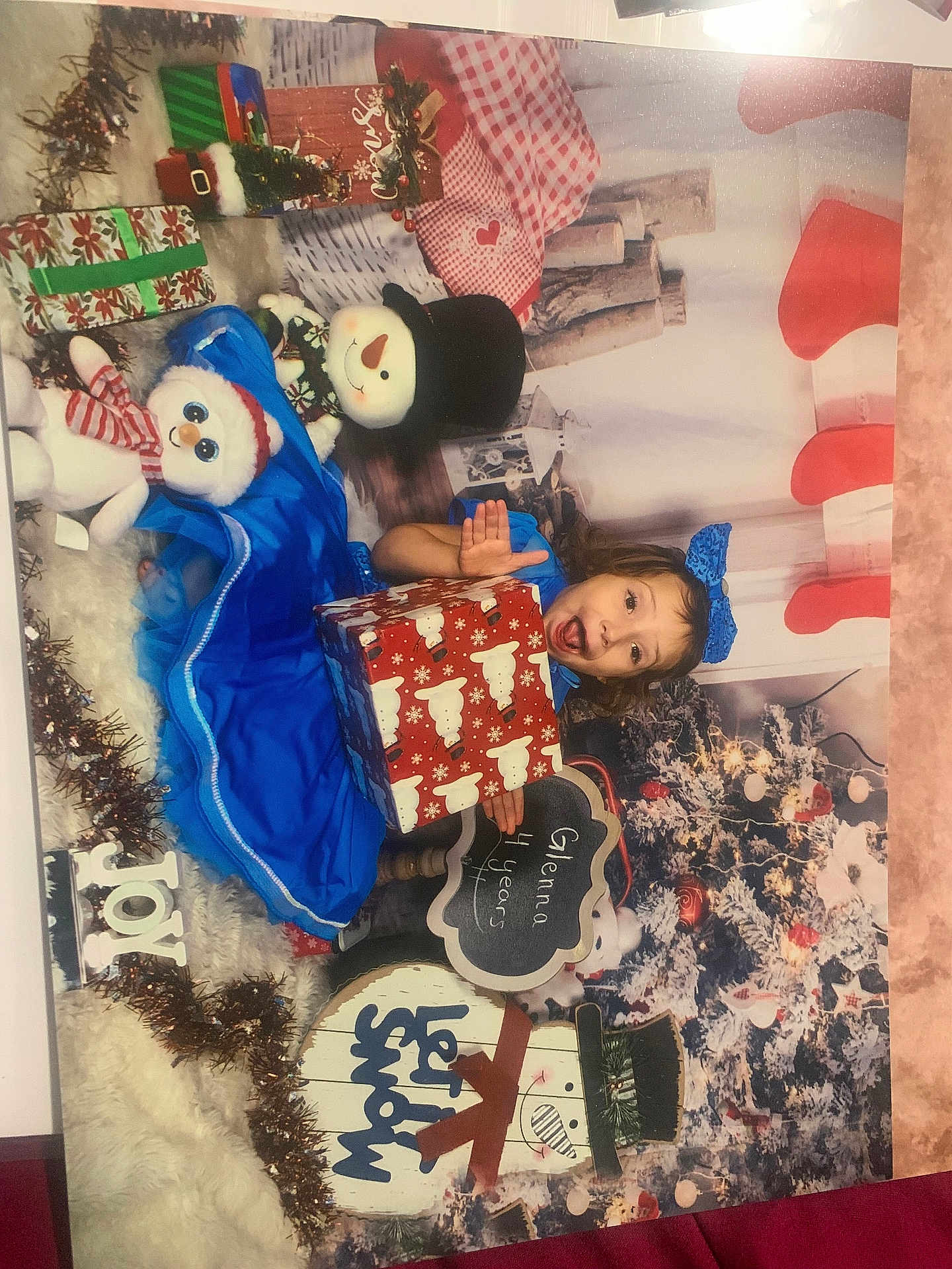 Glenna is registered to the contest to win money with this photo: child, girl, blue_dress, bow, gift_box, holiday, christmas_tree, snowman, plush_toy, decorations, festive, holiday_sign, joy, let_it_snow, chalkboard_sign, smiling, celebration, holiday_season, indoors, holiday_photo