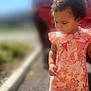 car, casual_wear, child, curious, curly_hair, cute, daylight, exploring, floral_pattern, outdoor, pavement, person, pink_clothing, portrait, romper, sidewalk, standing, sunlight, toddler, young_child