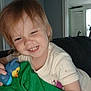 Chloe is registered to the contest to win money with this photo: toddler, child, smiling, toy, blue_toy, blanket, green_blanket, indoor, person, face, happy, hair, clothing, couch, home, room, furniture, childhood, cute, playful