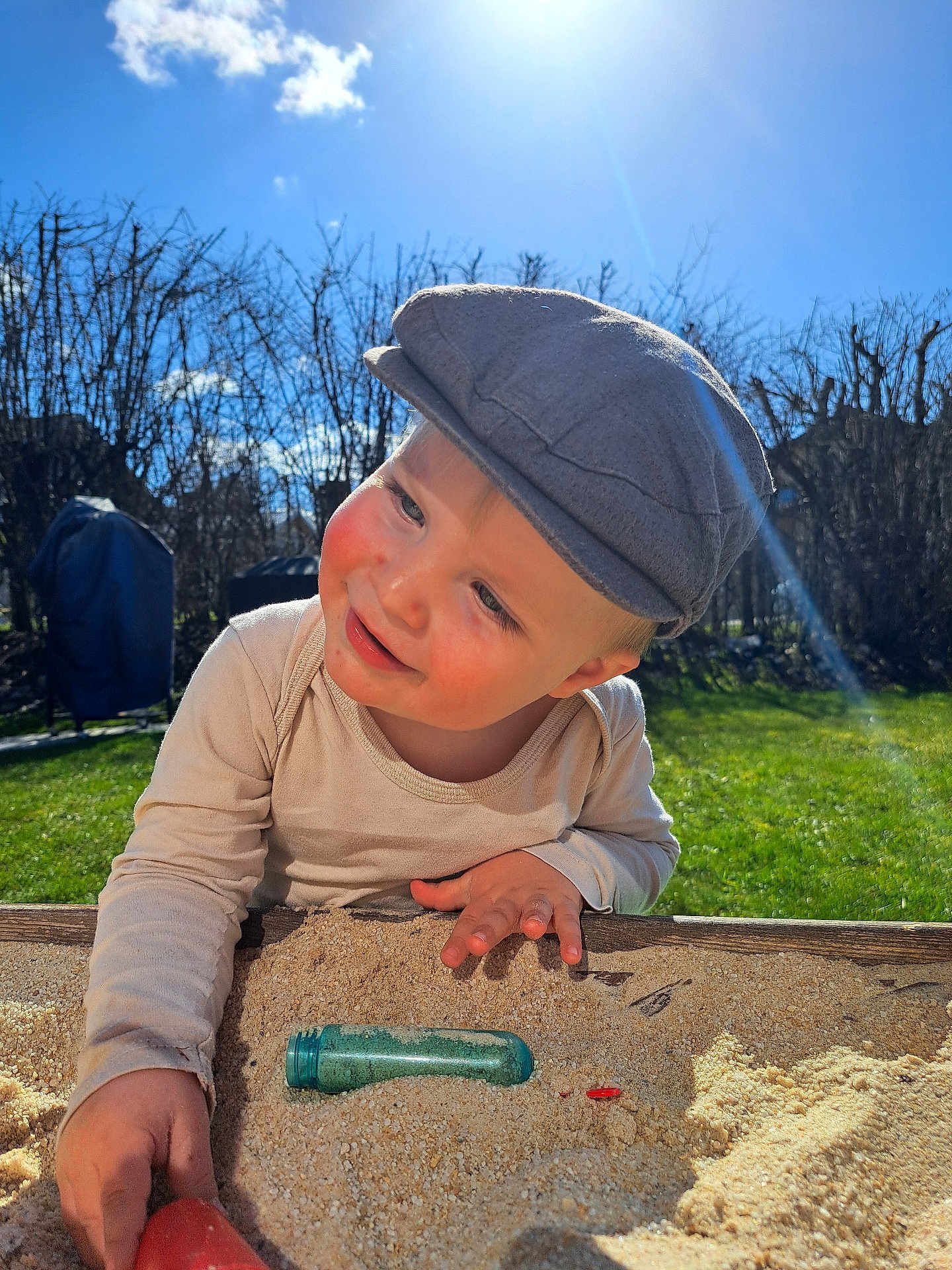Lysio participe au concours pour gagner de l'argent avec cette photo : child, toddler, sandbox, sand, hat, cap, sunlight, outdoor, grass, smile, happy, face, hand, toy, play, backyard, sunflare, blue_sky, cloud, cheek