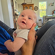 Josephine is registered to the contest to win money with this photo: baby, child, cute, expression, face, furniture, hand, holding, home, human, indoor, infant, jeans, living_room, person, shirt, skin, smile, window, wood