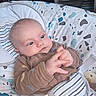 Josephine is registered to the contest to win money with this photo: baby, infant, child, hand, face, clothing, seat, baby_seat, pattern, striped, brown_outfit, indoor, furniture, bookshelf, comfort, cute, portrait, closeup, expression, young