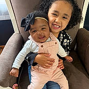 Serenity joined the competition — help win amazing prizes! children, siblings, baby, toddler, girl, infant, smiling, portrait, indoor, armchair, curly_hair, hair_bow, headband, overalls, floral_clothing, white_shirt, socks, family, sitting, happy