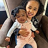 children, siblings, baby, toddler, girl, infant, smiling, portrait, indoor, armchair, curly_hair, hair_bow, headband, overalls, floral_clothing, white_shirt, socks, family, sitting, happy