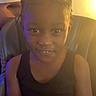 Kamiyah joined the competition — help win amazing prizes! child, girl, portrait, sitting, indoors, living_room, chair, dark_clothing, black_top, braided_hair, hair_bows, smiling, looking_at_camera, face, eyes, head, shoulders, warm_lighting, blue_lighting, photography
