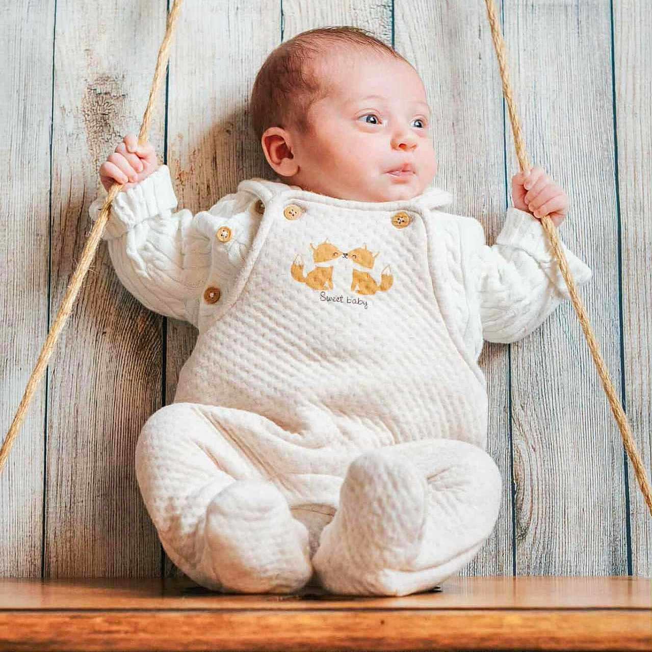 Lola a rejoint le concours — aidez-le/la à gagner de superbes lots ! baby, buttoned_outfit, child, cozy, cute, eyes, face, hands, indoor, infant, photography, playful, portrait, rope, seated, soft_texture, swing, white_clothing, wooden_background, wooden_swing