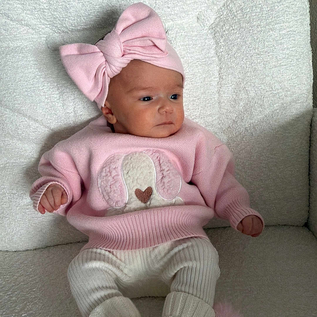 Elys joined the competition — help win amazing prizes! apparel, baby, child, comfortable, couch, cozy, cute, dog_applique, indoors, infant, knitted_booties, newborn, pink_bow, pink_sweater, pom_poms, portrait, seated, soft_texture, warm_clothing, white_pants