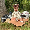 baby, infant, child, six_months, football, football_helmet, football_cleats, bow, headband, sweater, smiling, sitting, portrait, outdoor, woodland, trees, grass, blanket, sports_theme, milestone_photo