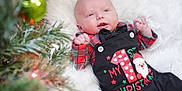 Spencer joined the competition — help win amazing prizes! baby, infant, christmas, holiday, festive_clothing, plaid, black_overalls, santa_claus, white_blanket, christmas_tree, ornament, green, red, smiling, cute, indoor, celebration, portrait, child, seasonal
