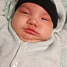 baby, infant, face, headwear, hat, beanie, clothing, sweater, blanket, lying_down, expression, chubby_cheeks, indoor, portrait, skin, person, child, young, cute, screenshot