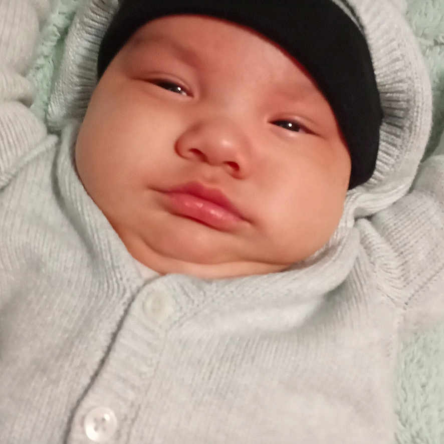 Josiahhawk joined the competition — help win amazing prizes! baby, infant, face, headwear, hat, beanie, clothing, sweater, blanket, lying_down, expression, chubby_cheeks, indoor, portrait, skin, person, child, young, cute, screenshot