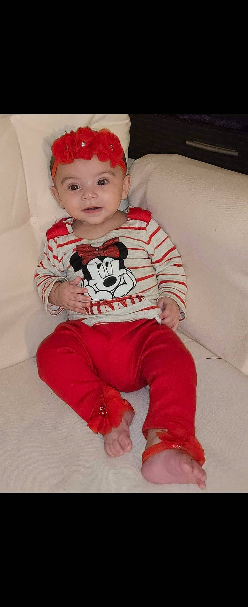 Cheyenne is registered to the contest to win money with this photo: baby, baby_toddler_clothing, child, comfort, costume_hat, couch, face, facial_expression, head, headwear, leg, pattern, person, pink, red, sitting, sleeve, smile, t_shirt, textile