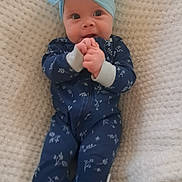 Annabelle joined the competition — help win amazing prizes! baby, infant, child, headband, bow, onesie, blue_clothing, floral_pattern, blanket, textured_blanket, hands, cute, lying_down, portrait, indoors, face, expression, clothing, person, adorable