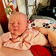 Saige joined the competition — help win amazing prizes! newborn, baby, infant, sleeping, portrait, close_up, face, eyes_closed, pink_clothing, onesie, blanket, cuddled, adult_arm, tattoo, home, indoors, bookshelf, books, cozy, family