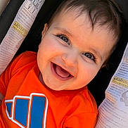 Leon joined the competition — help win amazing prizes! baby, child, smile, happy, orange_shirt, car_seat, warning_label, face, portrait, infant, cute, young_child, eyelashes, clothing, seatbelt, seat, person, cheerful, closeup, indoors