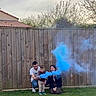 adult, backyard, blue_smoke, casual_clothing, celebration, child, cloudy_sky, family, fence, fun, grass, happy, kneeling, nature, outdoor, people, playing, smoke, toddler, tree