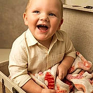 Bryer is registered to the contest to win money with this photo: baby, child, toddler, smiling, laughing, portrait, indoor, basket, blanket, cozy, seated, clothing, shirt, face, eyes, mouth, furniture, home, warm_lighting, happy