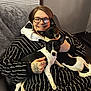 black_and_white, blanket, couch, cozy, dog, ear, face, glasses, happy, human_hand, indoor, living_room, person, pet, seated, short_hair, smiling, striped_clothing, tattoo, window_blind