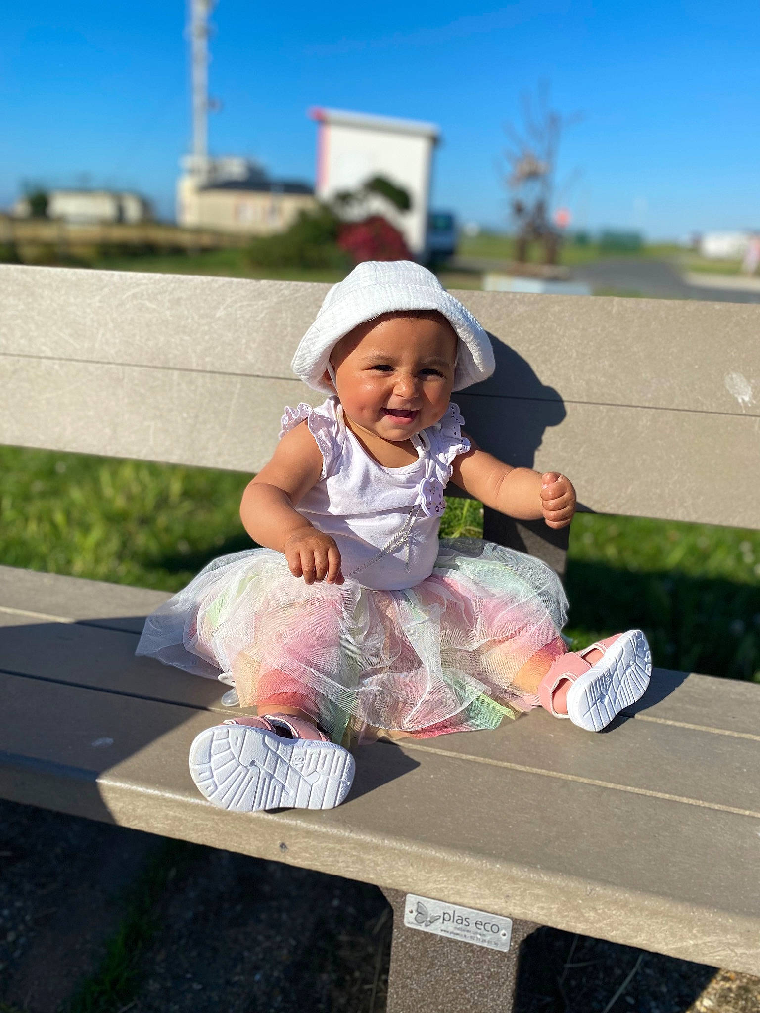 Nora a rejoint le concours — aidez-le/la à gagner de superbes lots ! baby_toddler_clothing, cap, fun, grass, happy, hat, headwear, joy, leisure, outdoor_furniture, person, pink, recreation, shoe, shorts, sitting, sky, smile, sneakers, summer