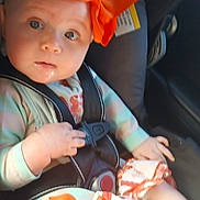 Kinsley Jones joined the competition — help win amazing prizes! baby, child, car_seat, orange_bow, infant, seatbelt, clothing, person, portrait, indoor, sunlight, cute, looking, seat, car, young_child, headband, expression, hands, apparel