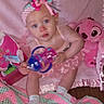 Kinsley Jones is registered to the contest to win money with this photo: baby, child, pink, headband, sippy_cup, blanket, crocheted_blanket, plush_toy, soft_toys, socks, indoors, cute, toddler, person, portrait, seated, floor, playtime, colorful, fabric