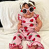 baby, infant, child, portrait, sitting, bed, pillow, sunglasses, headband, bow, strawberry, pink, outfit, romper, ruffles, barefoot, smiling, indoors, fashion, photography