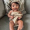 Giovanna joined the competition — help win amazing prizes! baby, child, infant, smiling, happy, portrait, sitting, couch, sofa, pillow, headband, bow, striped_clothing, dress, indoor, home, furniture, face, bare_feet, toddler