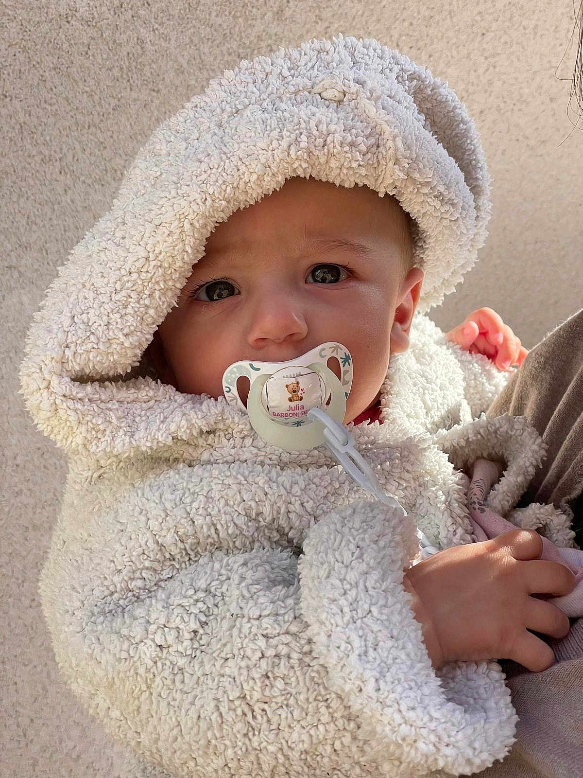 Julia participe au concours pour gagner de l'argent avec cette photo : baby, child, pacifier, hoodie, fluffy_clothing, hand, face, cute, infant, warm_clothing, portrait, closeup, young_child, skin, eyebrows, eyelashes, expression, outdoor, soft_texture, toddler