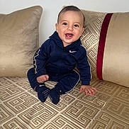 Wael participe au concours pour gagner de l'argent avec cette photo : baby, child, clothing, couch, cute, face, furniture, happy, home, indoor, nike, pattern, person, pillows, portrait, sitting, smiling, sock, tracksuit, young