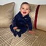 baby, child, clothing, couch, cute, face, furniture, happy, home, indoor, nike, pattern, person, pillows, portrait, sitting, smiling, sock, tracksuit, young