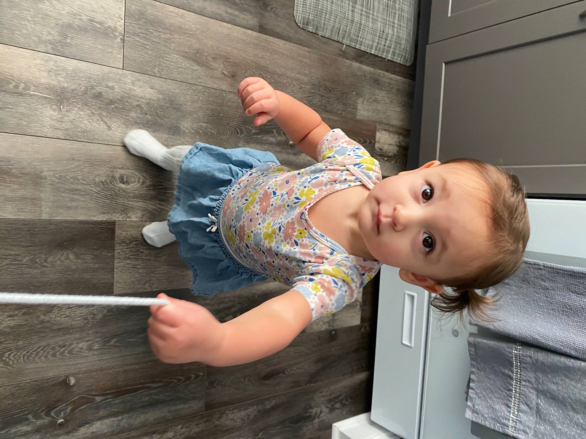 Kaya is registered to the contest to win money with this photo: baby, baby_products, baby_toddler_clothing, child, comfort, denim, flooring, fun, hand, happy, human_leg, joint, leisure, person, sitting, standing, t_shirt, toddler, tree, wood