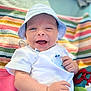 Léopold participe au concours pour gagner de l'argent avec cette photo : baby, infant, smiling, hat, white_shirt, whale_design, striped_blanket, colorful, happy, lying_down, hand, toy, playful, closeup, cute, outdoor, sunlight, skin, face, child