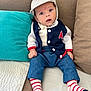 baby, child, infant, hat, striped_socks, blue_eyes, navy_vest, red_patch, couch, pillows, white_shirt, denim_pants, striped_hat, cute, curious, indoor, portrait, seated, cozy, comfortable