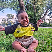 Joel is registered to the contest to win money with this photo: baby, child, grass, outdoor, park, tree, smiling, happy, person, greenery, nature, shorts, shirt, barefoot, daylight, cute, sitting, sunlight, cheerful, fun