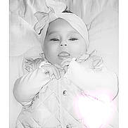Kenlie N Kylie is registered to the contest to win money with this photo: baby, infant, headband, bow, tongue, quilted_jacket, blanket, cute, playful, lying_down, face, child, cozy, soft, warm_clothing, adorable, portrait, indoor, newborn, glowing_heart