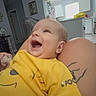 Ryder is registered to the contest to win money with this photo: baby, child, smiling, yellow_shirt, tattoo, indoor, home, kitchen, person, happy, laughing, toddler, face, human, furniture, casual_clothing, skin, arm, light, window