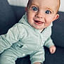 baby, child, infant, smiling, face, blue_eyes, onesie, sitting, indoor, couch, happy, cute, portrait, young, skin, expression, person, furniture, cozy, closeup