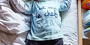 Kellyo participe au concours pour gagner de l'argent avec cette photo : baby, child, hat, blue_shirt, pants, blanket, cushion, bed, indoor, face, person, lying_down, toddler, expression, clothing, resting, toy, casual, headwear, infant